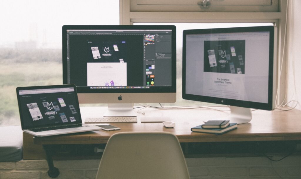 Pantallas de PC para el diseño web Stylish and efficient workspace with multiple monitors, laptop, and smartphone, showcasing a web design project.